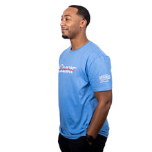 MD Anderson employee wearing a light blue shirt featuring the white cancer strikethrough logo on the chest and the white MD Anderson logo on the sleeve.