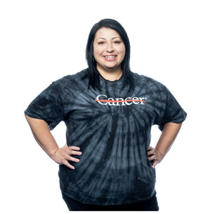 MD Anderson employee wearing a black tie-dye t-shirt featuring the white cancer strikethrough logo on the front, with the full MD Anderson logo displayed on the sleeve.