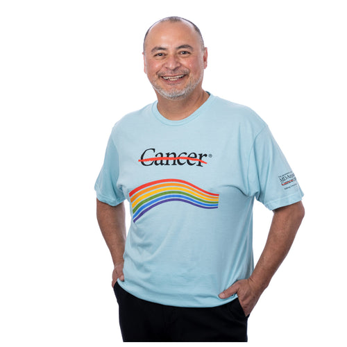 MD Anderson employee wearing a light blue t-shirt featuring the black cancer strikethrough logo on the chest area and multiple colors underneath, and the full MD Anderson logo on the sleeve.
