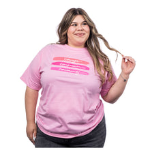 MD Anderson employee wearing a pink T-Shirt with a print in the middle featuring the words "courage, compassion, and community", also featuring the white cancer strikethrough logo on the sleeve.