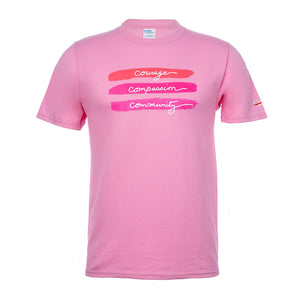 Pink T-Shirt with a print in the middle featuring the words "courage, compassion, and community", also featuring the white cancer strikethrough logo on the sleeve.
