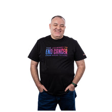 MD Anderson employee wearing a black shirt featuring the multicolor gradient tagline "The Journey to End Cancer from Cause to Cure".
