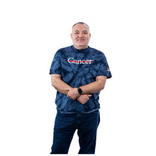 MD Anderson employee wearing a blue tie-dye short-sleeve t-shirt with the white Cancer strikethrough logo on the chest.