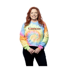 MD Anderson employee wearing a tie-dye long sleeve shirt featuring the black cancer strikethrough logo on the chest and the black MD Anderson logo on the sleeve.