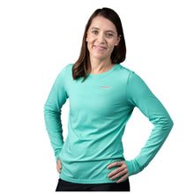 MD Anderson employee wearing a turquoise long sleeve shirt featuring the white cancer strikethrough logo on the upper left chest area.