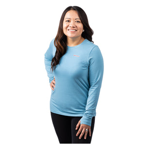 MD Anderson employee wearing a blue long sleeve shirt featuring the white cancer strikethrough logo on the upper left chest area.