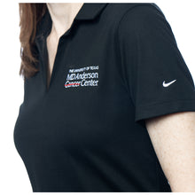 MD Anderson employee wearing a black Nike polo with a V-neck featuring the white MD Anderson logo on the chest area and the Nike logo on the sleeve.