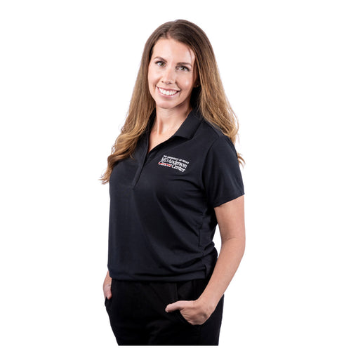 MD Anderson eomployee wearing a black performance polo featuring the full white MD Anderson logo on the upper left side of the chest area.