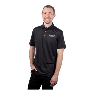 MD Anderson employee wearing a black Peter Millar polo featuring the full white MD Anderson logo on the upper left chest area.