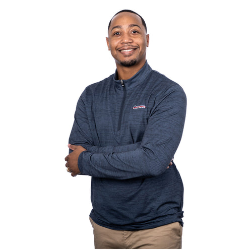 MD Anderson employee wearing a navy Travis Mathew 1/4 zip featuring the white cancer strikethrough logo on the upper left chest area.