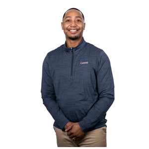 MD Anderson employee wearing a navy Travis Mathew 1/4 zip featuring the white cancer strikethrough logo on the upper left chest area.