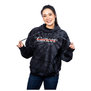 MD Anderson employee wearing a black tie-dye hoodie featuring the white cancer strikethrough logo on the chest area.