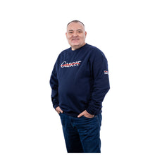 MD Anderson employee wearing a navy blue long-sleeve crewneck sweatshirt featuring the white Cancer strikethrough logo across the chest and the UT MD Anderson logo on the sleeve.