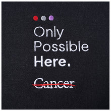 Closeup of tagline "Only Possible Here and the white cancer strikethrough logo.