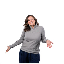 MD Anderson employee wearing a heather gray long-sleeve 1/4 zip ANTIGUA pullover featuring the white Cancer strikethrough logo on the left chest and side zipper pockets.
