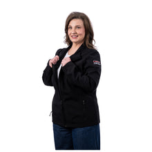 MD Anderson employee wearing a black long-sleeve soft shell jacket with a full front zipper, stand-up collar, side zipper pockets, and the full white UT MD Anderson logo on the left sleeve.