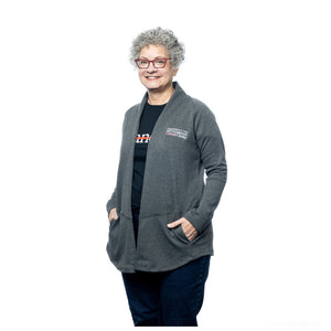 MD Anderson employee wearing a gray cardigan with pockets, featuring the white MD Anderson logo on the chest area.