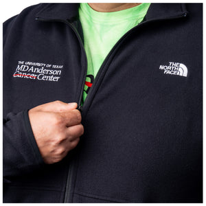 Closeup of MD Anderson employee wearing a black North Face fleece jacket featuring the white MD Anderson logo on the right side of the chest and the white North Face logo on the left side of the chest, featuring a full zipper and front zippered-pockets.