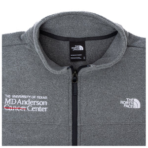 Close-up of gray North Face jacket with a full zip in the middle, featuring the white MD Anderson logo on the right side of the chest, and the white North Face logo on the left side of the chest. 