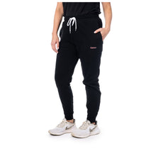 MD Anderson employee wearing black fleece joggers featuring the white cancer strikethrough logo on the upper left thigh area.