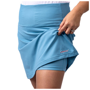 Lagoon blue skort featuring the white cancer strikethrough logo on the bottom seam showing the shorts underneath.