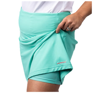 Turquoise skort featuring the white cancer strikethrough logo on the bottom seam showing the shorts underneath.