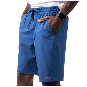 MD Anderson employee wearing blue shorts with side pockets featuring the white cancer strikethrough logo on the bottom left seam.