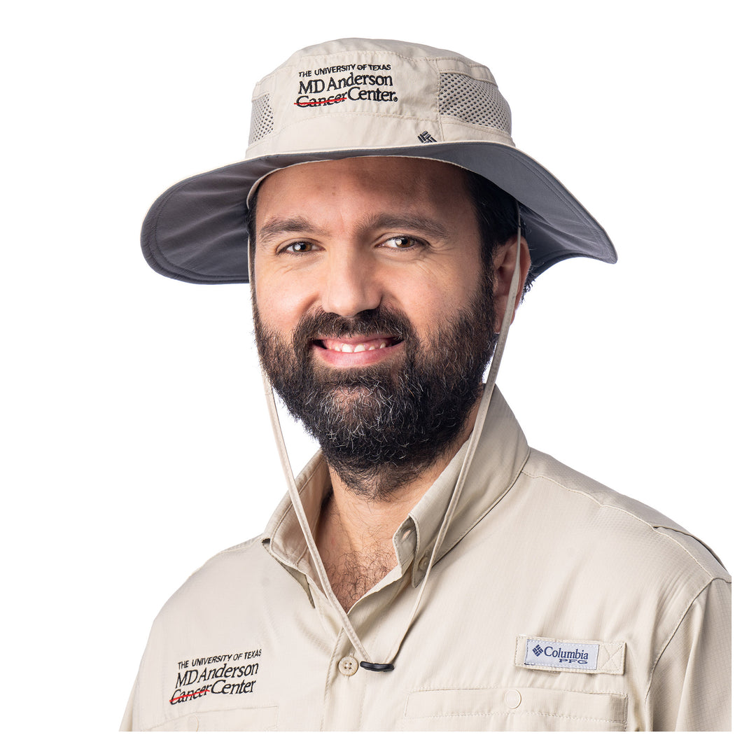 MD Anderson employee wearing a tan Columbia hat featuring the full black MD Anderson logo.