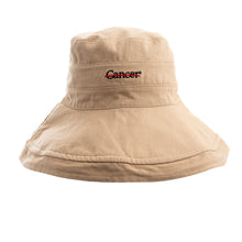 Tan bucket hat featuring the black cancer strikethrough logo in the middle.