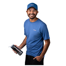 MD Anderson employee wearing a blue cap featuring the white cancer strikethrough logo in the middle, also sporting the blue shirt featuring the white cancer strikethrough logo on the upper left chest area.