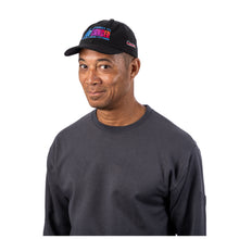 MD Anderson employee wearing a black baseball cap featuring the colorful "The Journey to End Cancer" gradient graphic on the front and the white Cancer strikethrough logo embroidered on the side.