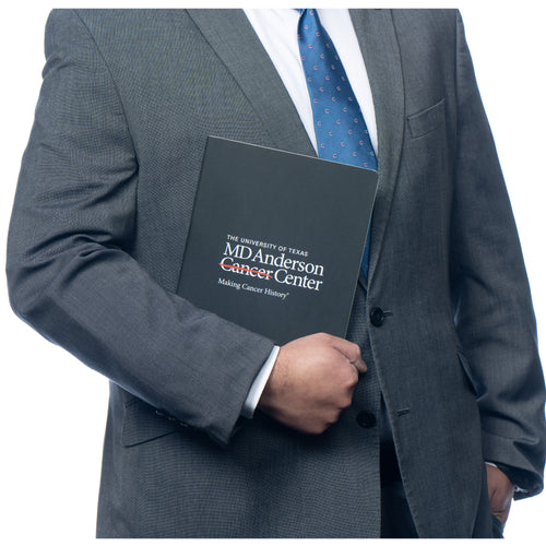 MD Anderson employee holding a black Moleskine journal featuring the white MD Anderson logo.