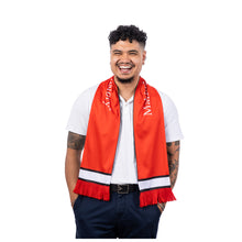 MD Anderson employee wearing a red knit soccer scarf featuring white-and-black stripe accents, fringe ends, and "Making Cancer History" printed in white along the sides.