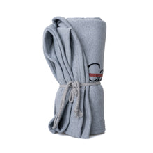 Gray sweatshirt blanket with the black cancer strikethrough logo on the bottom corner, rolled and tied in a knotted rope.