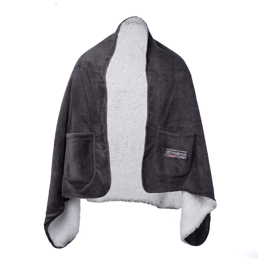 Gray shawl blanket featuring two side pockets and the full white MD Anderson logo on the side pocket.
