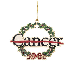 Metal ornament in the shape of a holiday wreath with a red bow featuring the black cancer strikethrough logo in the middle.