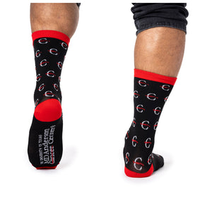 MD Anderson employee wearing black socks with red top hem, edges of toes, and sole, featuring the white strikethrough 'C' pattern, with the full MD Anderson logo at the bottom of the sock.