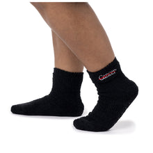 MD Anderson employee wearing black fuzzy socks with the white cancer strikethrough logo on the side and non-slip grip bottoms.