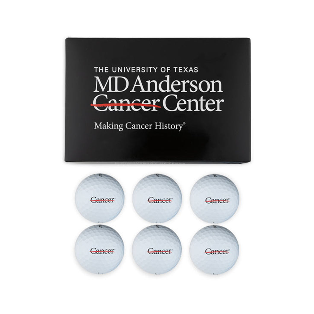 Set of 6 white golf balls featuring the black cancer strikethrough logo, along with the packing box which features the white MD Anderson logo.